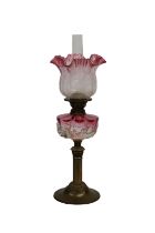 A late 19th century brass oil lamp with clear and rose coloured glass shade and oil reserve clear
