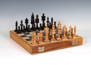 A cased chess set with carved soapstone pieces together with carved wooden chess pieces, both