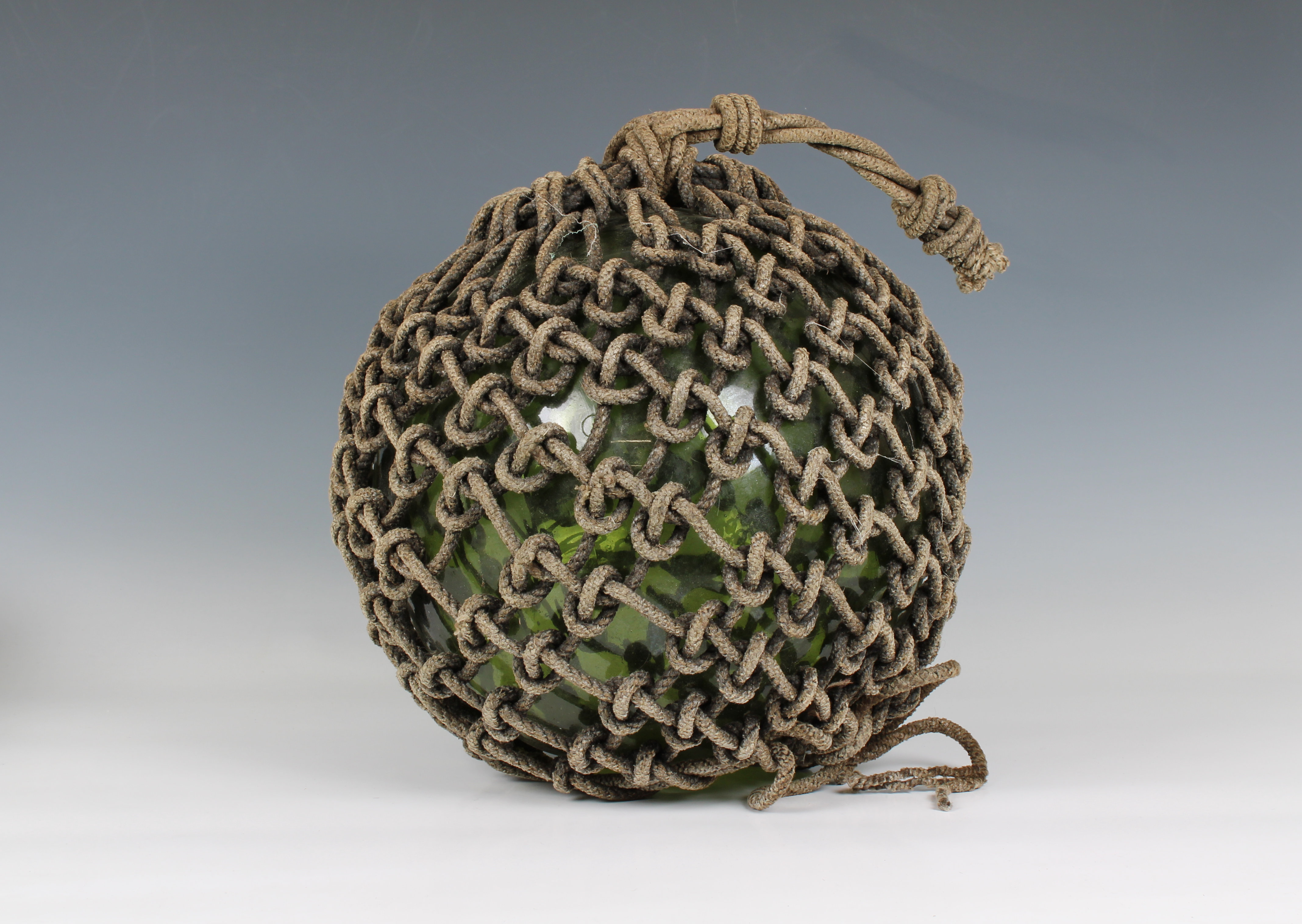 A large 19th century blown glass green fishing float
