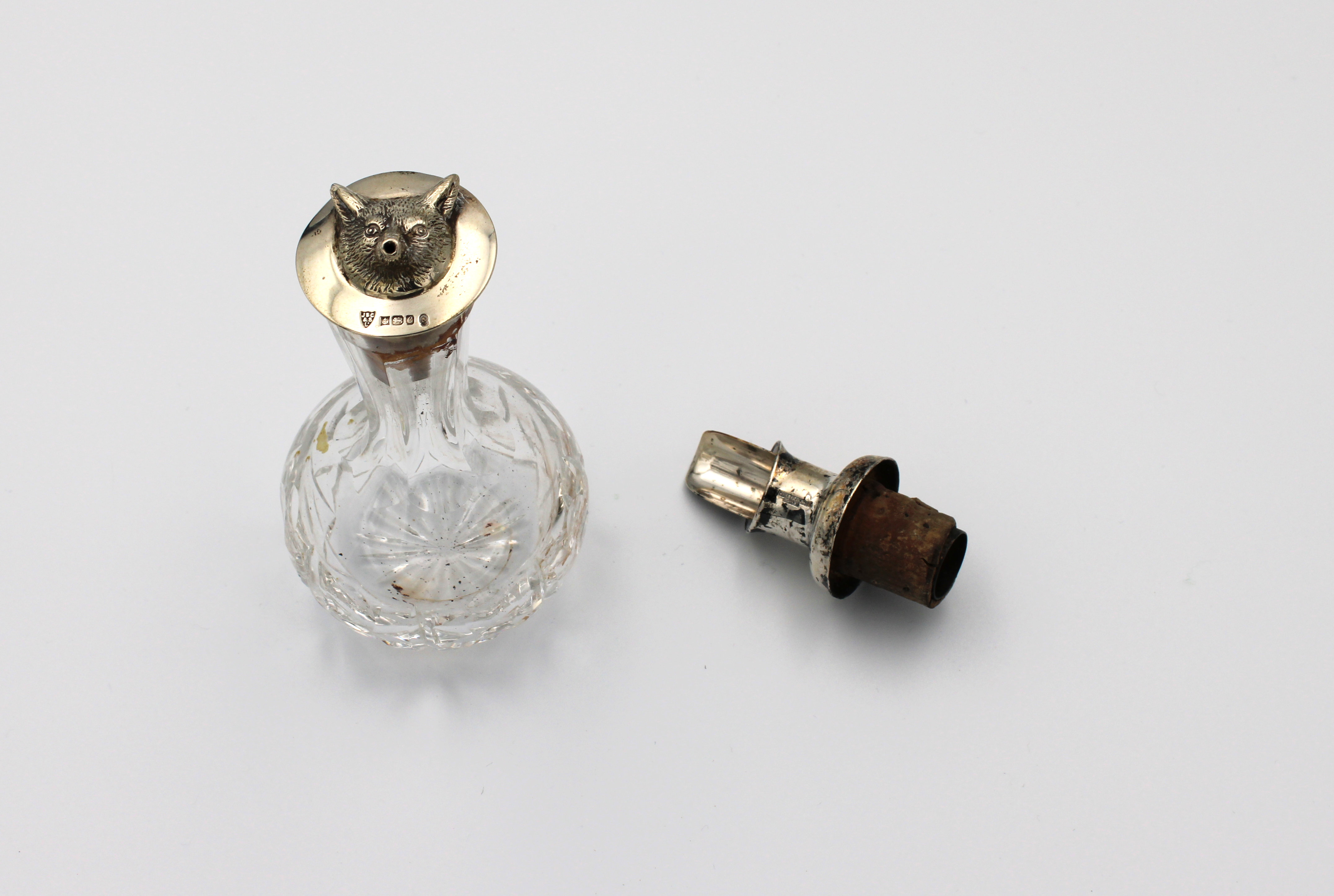 A silver mounted cut glass oil dispenser with fox head finial to stopper