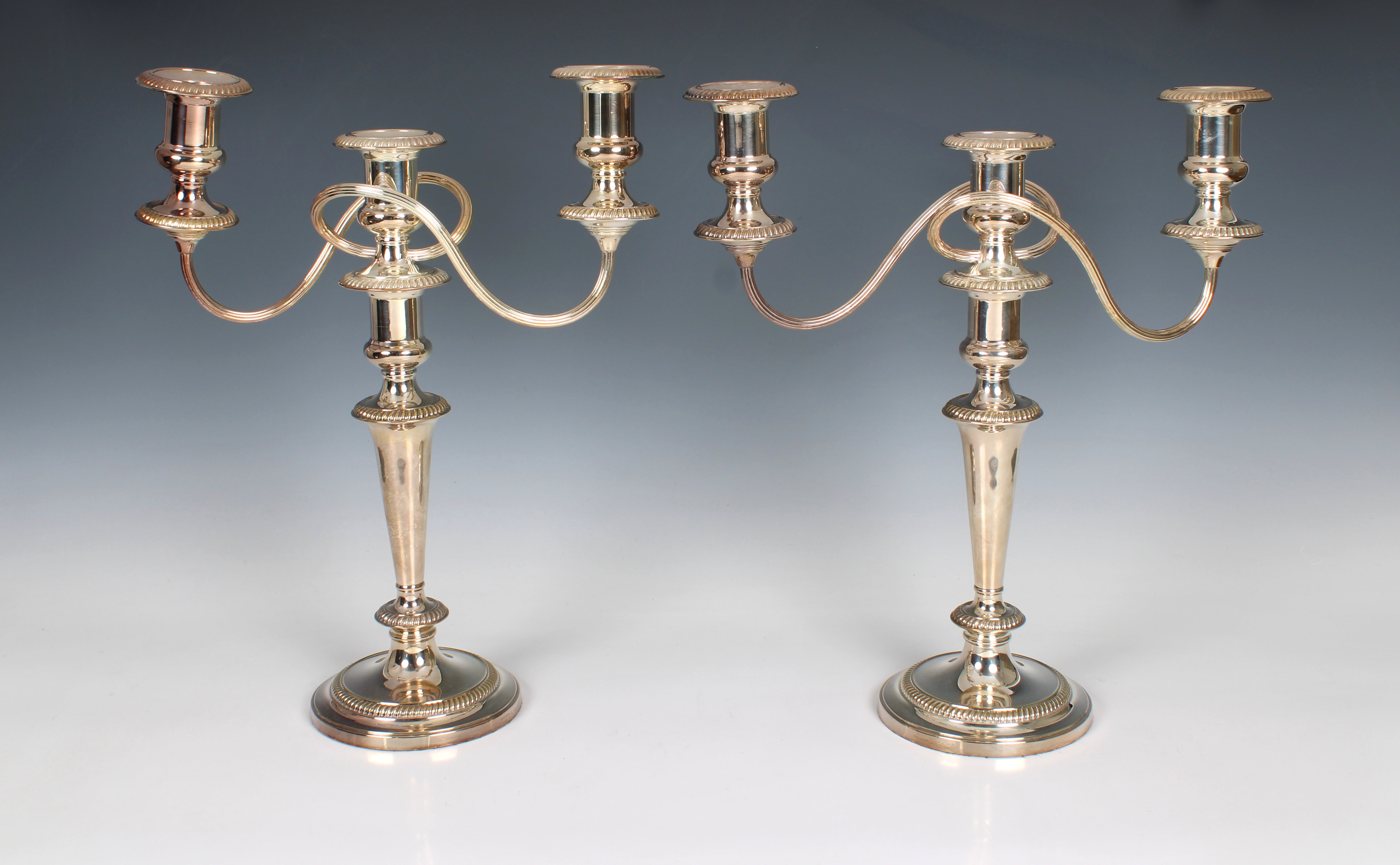 A pair of silver plate on copper twin branch candelabra