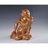 A Burmese Mandalay carved, lacquered and jewelled gilt wood figure of a seated monk