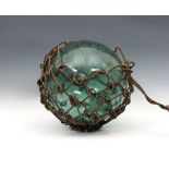 A large 19th century blown glass light green fishing float