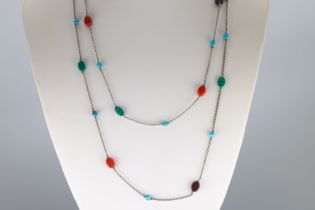 A long silver chain necklace set with numerous semi-precious stones