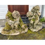 Two composite stone garden statues of cavorting cherubs