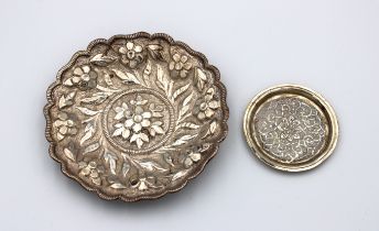 A white metal bowl heavily chased with floral decoration