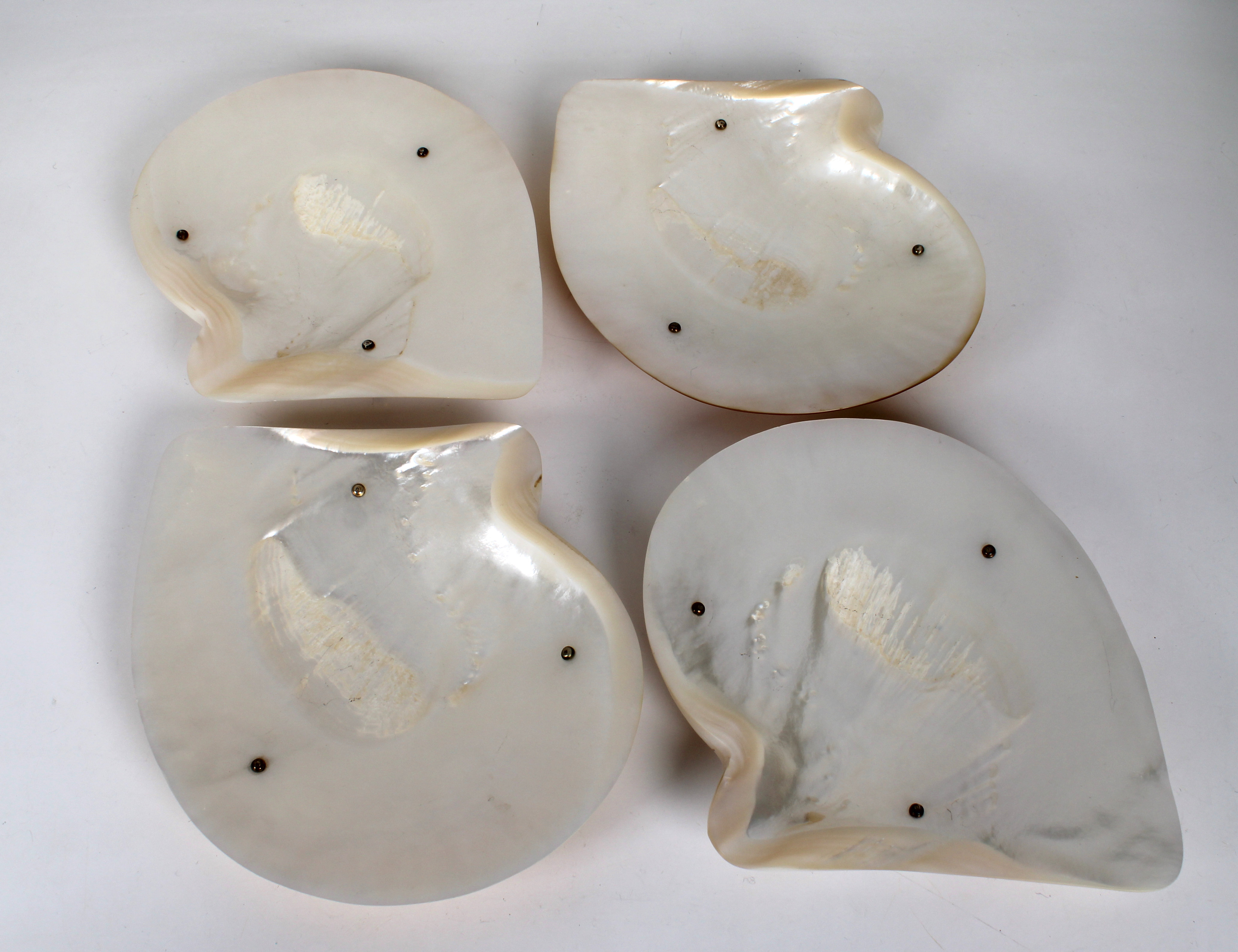 Four mother-of-peal abalone shell caviar dishes raised on silver gilt baluster feet