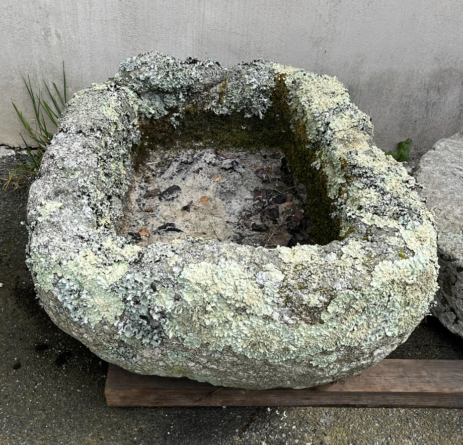 A weathered rounded rectangular granite trough