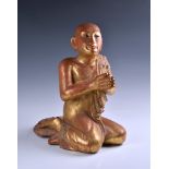 A Burmese Mandalay carved and jewelled gilt wood figure of a seated monk