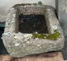 A weathered rounded rectangular granite trough