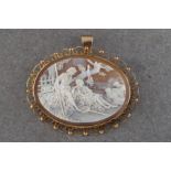 A shell cameo brooch of a courting couple in a pastoral scene in a 9ct gold mount