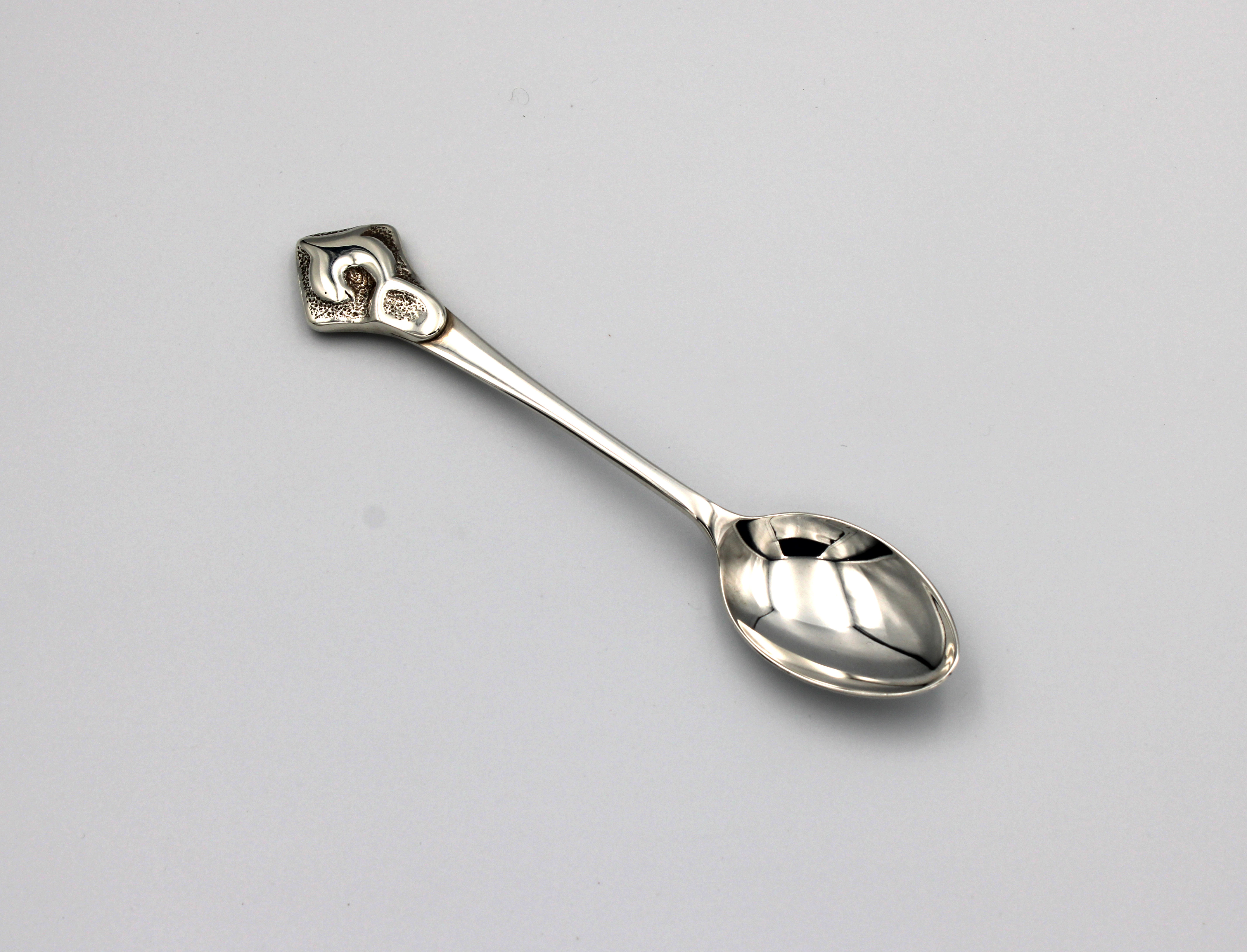 A heavy silver spoon with a decorative Art Nouveau style finial