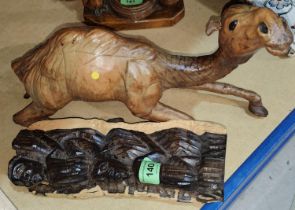 A leather model of a reclining camel with glass eyes length 39cm and a hardwood carving of a