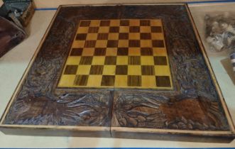 A carved wooden folding chessboard with chess pieces and checkers, parrot carved decorative