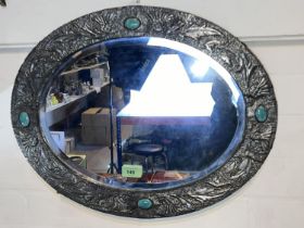 An Arts and Crafts Glasgow style oval wall mirror in pewter embossed with scrolling thistle