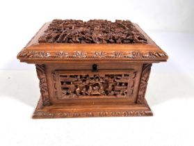 A Chinese carved wooden jewellery casket with raised relief carved panels of intricate scenes,