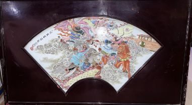 A Chinese ceramic fan shaped polychrome panel of battle scene warriors clashing on horseback in