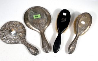 A silver back hand mirror and brush with embossed flowers and butterflies, Chester 1913; a heavily