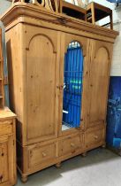 A Victorian style pine triple wardrobe with central mirror and 3 base drawers