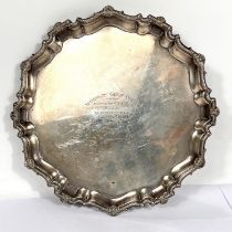 A hallmarked silver salver with scalloped shell border and scroll feet, inscribed, Birmingham