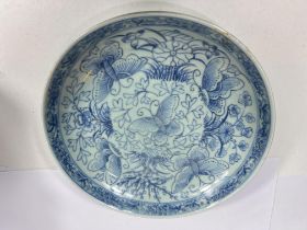 A Chinese celadon dish with butterfly decoration in blue with mark to base, re-glued section, 22cm