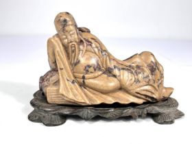 A Chinese Mutton Jade coloured stone figure of reclining deity finely detailed with shaped darker