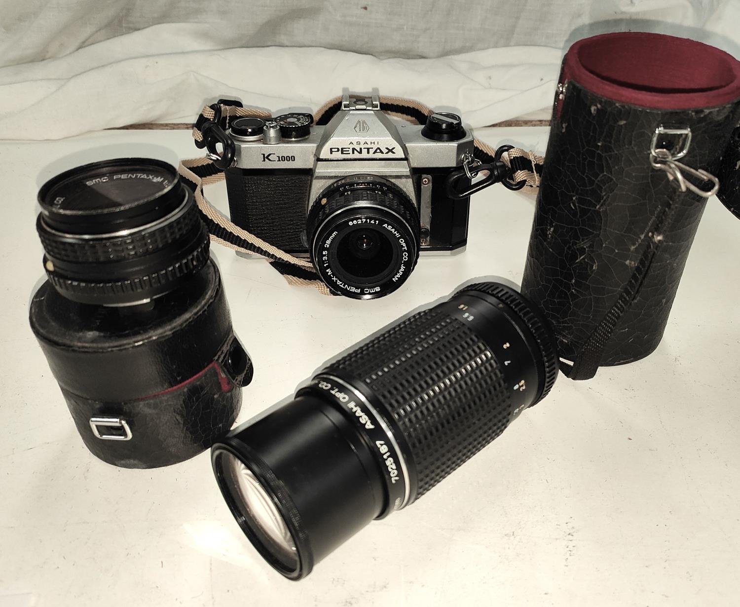 A Pentax K1000 SLR camera with three lenses, 80mm - 200mm, 28mm and 50mm