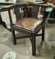 A Georgian style corner armchair in mahogany and hide, with extensive carved decoration