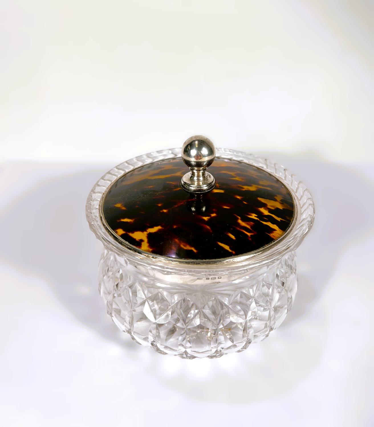 A large circular cut glass tray; powder bowl with tortoise shell and a hallmarked silver lid, London