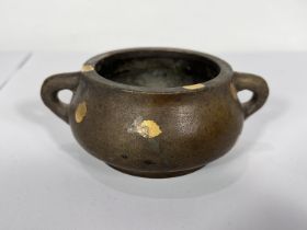 A Chinese bronze censor squat form, circular base with two hoop handles, applied areas of gilt, mark