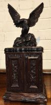 A 19th Black Forest carved cigar humidor in the form of eagle standing atop cupboard with double