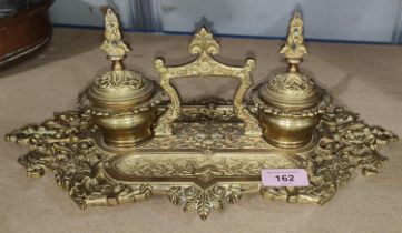 A brass desk organiser with ink wells and en trays to each side in the French manner, length 37cm