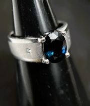 A gent's white metal dress ring with oval blue sapphire (11.3 x 8.7 x 4.85mm) in 4 claw setting, the