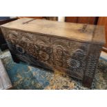 An Arts & Crafts oak coffer chest with highly carved front with cast iron hinges and plaque, plank