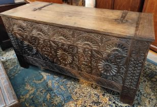 An Arts & Crafts oak coffer chest with highly carved front with cast iron hinges and plaque, plank