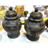 A pair of Chinese bronze lidded vases with silvered relief decoration of domestic scenes, text to