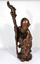 A Chinese hardwood carving of a sage with stick and fruit, ht. 50cm