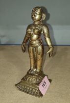 A brass sculpture of a deity with detailed incised decoration, 16cm