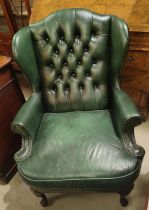 A traditional style mid 20th century wing back armchair in deeply buttoned green hide on cabriole