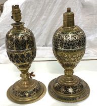 A Middle Eastern pair of brass table lamps of baluster form with silvered line and extensive