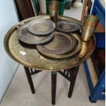 A Middle Eastern circular folding table with etched decoration, similar brass including dishes, mugs