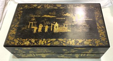 A Japanese lacquer writing box with gilt decoration of pagodas and domestic scenes.