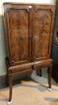 A reproduction mahogany drinks cabinet with 2 figured doors and 2 drawers