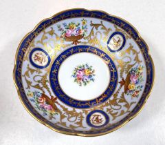 A circular dish with scalloped border with blue, gilt and floral decoration on 3 feet, with blue and