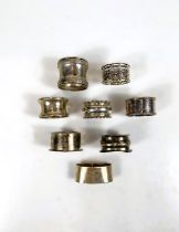 Seven hallmarked silver assorted napkin rings, 4.25oz; a white metal napkin ring