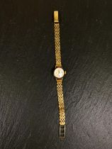 A ladies 9 carat hallmarked gold Omega wristwatch on yellow metal bark effect strap, stamped 37 5,