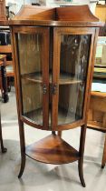 A mahogany inlaid floor standing corner display unit with bow front, double doors, shelf under