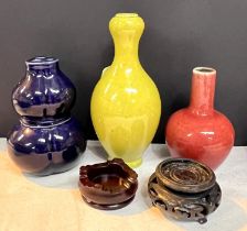 Three small Chinese monochrome vases, yellow and red vases on stands and a dark blue double gourd