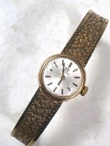 A ladies 9 carat hallmarked gold OMEGA wristwatch with integral hallmarked gold bark effect strap,