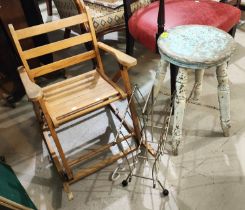 A vintage child's folding rocking chair and a vintage painted stool and a 1960's magazine rack.